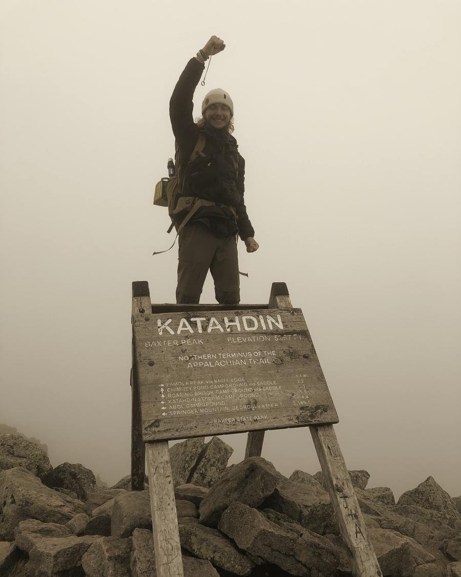 Jordan at the Katahdin summit sign in Maine, the northern end of the Appalachian Trail, fist raised